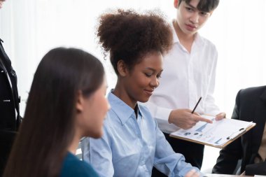 Genç Afrikalı iş kadını birlikte çalışıyor ve şirket ofisinde çok kültürlü iş arkadaşlarıyla tartışıyor. Profesyonel ve çeşitlilik takım çalışması masada iş planını tartışır. Uyum