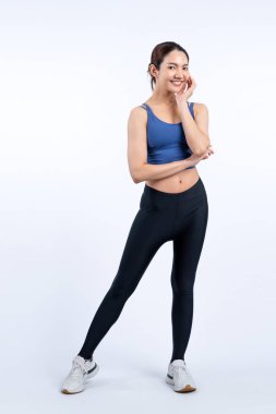 Spor giyim portresindeki tüm vücut Asyalı kadın gülümsüyor ve neşeli bir jest yapıyor. Çekici bir kızla egzersiz yapmak sağlıklı yaşam tarzını sürdürmeye yöneliktir. İzole edilmiş arka plan Vigorous