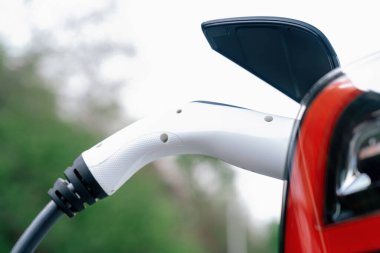 Kapalı EV şarj kolu fişe takıldı veya elektrikli arabaya bağlandı, EV araba aküsünü temiz çevre için sıfır CO2 emisyonu ile alternatif ve sürdürülebilir enerjiyle şarj etti. Kalıcı