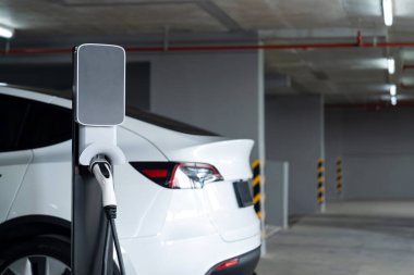 Alış veriş merkezinin otoparkında EV elektrikli araba şarjı şehir merkezindeki sürdürülebilirlik yaşam tarzını yeşil, temiz, yeniden şarj edilebilir elektrikli araç iç organları ile gösteriyor.