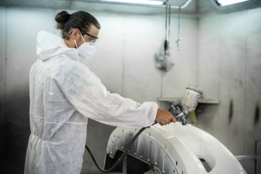 Koruyucu ekipmanlı otomotiv işçisi araba kaportasına sprey tabanca ya da oda atölyesindeki solunum boyasıyla renk boyası uyguluyor. Tamir için araba boyama servisi. Oxus.