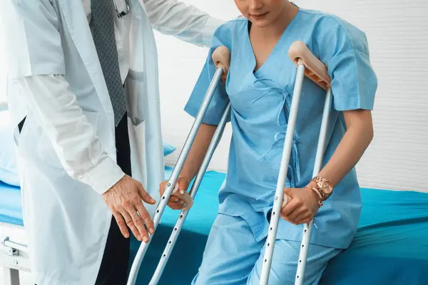 Doktor hastanede koltuk değnekli hastayla ilgileniyor. Fizyoterapist ve bacak yaralanması konsepti. Jivy