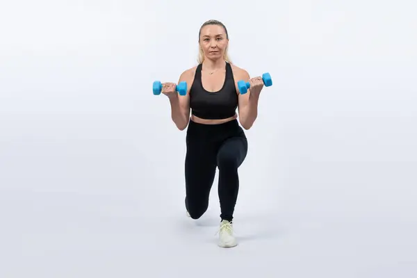 stock image Full body length shot active and sporty senior woman lifting dumbbell during weight training workout on isolated background. Healthy active physique and body care lifestyle for pensioner. Clout