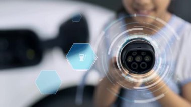 Kameranın önüne odaklanmış EV şarj cihazı fütüristik çevre dostu enerji altyapısı pictogram hologramını gösteriyor. EV araba şarjı sürdürülebilir güç için yenilenebilir enerji kullanıyor. İnceleyin