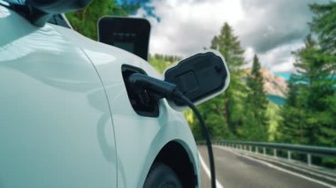 Elektrikli araç konsepti, yeşil çevre için yenilenebilir ve temiz enerjiyle çalışan EV otomobilinin varış noktasına ulaşmadan önce ormandaki şarj istasyonunun enerjisini şarj etmek için durur..
