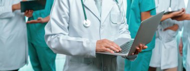 Hastanede dizüstü bilgisayar ve tabletle birlikte çalışan doktor hemşire ve sağlık uzmanlarına sahip tıbbi personel ekibi. Panoramik pankartta tıbbi işyeri ve sağlık hizmetleri topluluğu. Neoterik