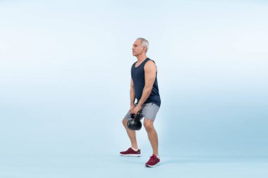 Vücut uzunluğu tam, atletik ve sportif yaşlı bir adam izole edilmiş arka planda vücut çalışması için kettlebell ile hiçbir şey yapmıyor. Emeklilikten sonra sağlıklı, aktif bir fiziğe ve vücut bakımına sahip. Etki