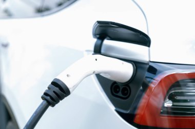 Elektrikli araç portuna bağlı EV şarj prizi kolu şarj istasyonundan şarj oluyor. Modern tasarlanmış EV araba ve daha iyi bir gelecek konsepti için temiz enerji sürdürülebilirliği. Eşzamanlama