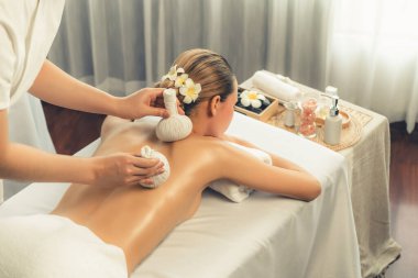 Sıcak bitkisel top spa masaj vücut tedavisi, masör kadın vücuduna nazikçe şifalı bitki torbası bastırıyor. Aromaterapi dinlenme sükuneti ve sükuneti kaplıca salonundaki atmosferi aydınlatıyor. Sessiz.