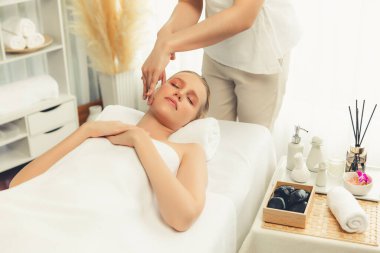 Kafkasyalı kadın stres önleyici kafa masajından ve lüks tatil beldesi ya da otel spa salonundaki modern ışık ortamında yüz güzelliği eğlencelerini şımartmaktan hoşlanıyor. Sessiz.