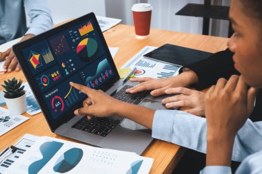 Çok ırklı analist ekibi toplantı masasındaki finansal verileri analiz etmek için BI Fintech yazılımı kullanıyor. Finansal konsol veri ekranında pazarlama göstergesi için analiz edilmiş grafikle birlikte. Uyum