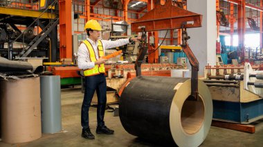 Makine operatörü çelik üretim makinelerini ustalıkla çalıştırıyor, metal fabrikasındaki ağır inşaat mühendisliği malzemeleri için silindir rulo çelik üretiyor. Örnek gösteriliyor