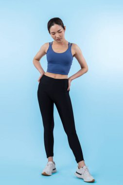 Spor giyim portresindeki tüm vücut Asyalı kadın gülümsüyor ve neşeli bir jest yapıyor. Çekici bir kızla egzersiz yapmak sağlıklı yaşam tarzını sürdürmeye yöneliktir. İzole edilmiş arka plan Vigorous