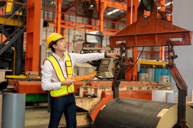 Makine operatörü çelik üretim makinelerini ustalıkla çalıştırıyor, metal fabrikasındaki ağır inşaat mühendisliği malzemeleri için silindir rulo çelik üretiyor. Örnek gösteriliyor