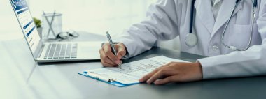 Doktor, laptoptaki tıbbi raporları dikkatle gözden geçir ve hastaların doktor muayenehanesinde etkili bir sağlık tedavisi için hastalık teşhisi koy. Profesyonel tıbbi değerlendirme. Neoterik