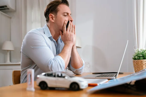Stressed and frustrated car design engineer put his head in his hand after discover flaw in vehicle design, working at home for automotive business while trying to find solution with laptop.Synchronos
