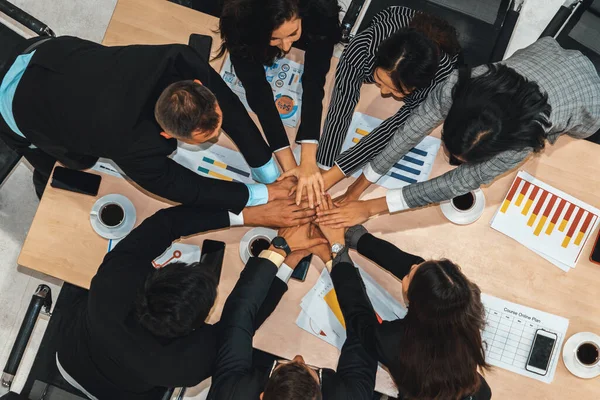 Happy business people celebrate teamwork success together with joy at office table shot from top view . Young businessman and businesswoman workers express cheerful victory show unity support . Jivy