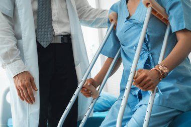Doktor hastanede koltuk değnekli hastayla ilgileniyor. Fizyoterapist ve bacak yaralanması konsepti. Jivy