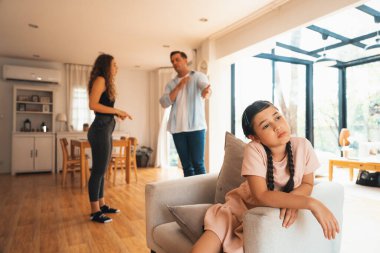 Sinirli ve mutsuz genç bir kız oturma odasında ebeveyninin tartışması yüzünden gerginliğin ortasında kanepede oturuyor. Sağlıksız ev hayatı ve travmatik çocukluk depresyona dönüşür.