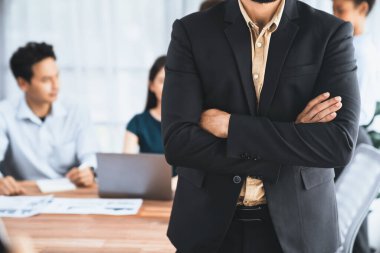 İş adamı, toplantı odasının arka planında çeşitli iş arkadaşlarıyla güven içinde poz veriyor. Çok kültürlü ekip iş başarısı için birlikte çalışır. Modern iş adamı portresi. Uyum