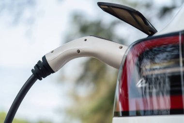 Kapalı EV şarj kolu fişe takıldı veya elektrikli arabaya bağlandı, EV araba aküsünü temiz çevre için sıfır CO2 emisyonu ile alternatif ve sürdürülebilir enerjiyle şarj etti. Kalıcı