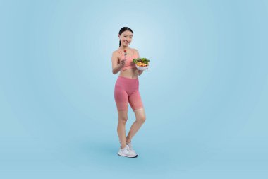 Spor giyim mağazasında elinde meyve ve sebze dolu salata kasesi tutan genç bir Asyalı kadın. Doğal gençlik ve uygun vücut yaşam tarzı izole edilmiş arka planda dengeli beslenme. Kuvvetli