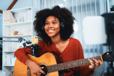 Güzel Afrikalı Kadın Etkilenen 'in sunucu kanalı akıllı telefondaki yayın stüdyosunda gitar çalarak şarkı söylüyor. Canlı sosyal medyada müzik blogcusu zamanı. Ses yaratıcısı kavramı. Tatlandırıcı.