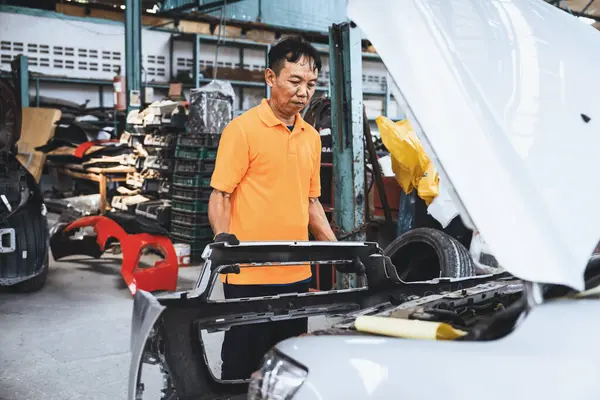 Skilled technician make refurbishment of bodywork in automotive car service, replacing or dissembling car bumper to damaged vehicle components. Oxus