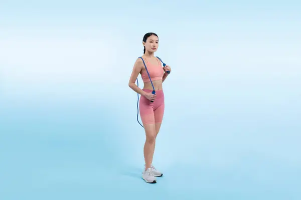 年轻精力充沛的亚洲女人穿着运动服 穿着跳跃或跳过的长袍 在工作室里摆出肖像画 背景孤立 有氧运动工具和健康的身体护理生活方式 精力充沛的 — 图库照片
