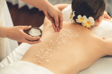 Lüks spa salonlarında sıcak mum ışığında cilt bakımı yaptıran kadın müşteri. Sağlık Spa vücut fırçasında tuz temizleme güzellik tedavisi. Sessiz.