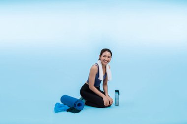 Atletik ve sportif Asyalı kadın yoğun kardiyo antrenmanından sonra dinleniyor. Stüdyoda sağlıklı egzersiz ve vücut bakımına uygun yaşam tarzı takibi izole edilmiş bir arka plan. Kuvvetli