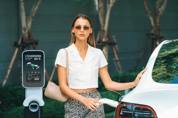 Młoda Kobieta Podróżuje Ładowania Samochodów Elektrycznych Zielonym Zrównoważonym Ogrodzie Miejskim — Zdjęcie stockowe