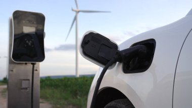Çevreyi korumak için rüzgar türbininden yeşil ve yenilenebilir enerjiyle çalışan şarj istasyonunda şarj edilen gelişmiş gelecek enerji altyapısı konsepti.