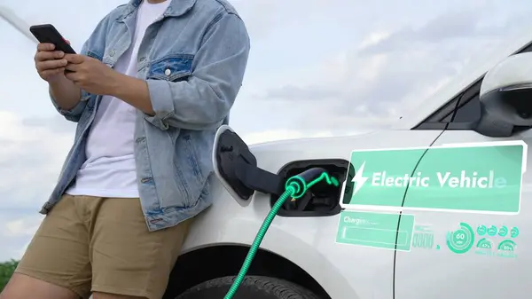 Asian Man Use Phone While Electric Car Recharge Energy Showing — Stock Photo, Image