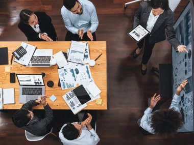 Modern toplantı odasındaki TV ekranında veri analizi paneliyle üst görünüm iş sunumu. İş adamlarının iş pazarlama stratejisini planlamak için beyin fırtınası yapması ya da birlikte çalışması. Uyum