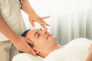 Beyaz adam stres önleyici kafa masajından ve lüks bir tatil beldesi veya otel spa salonundaki modern ışık ortamında yüz güzelliği eğlencelerini şımartmaktan hoşlanıyor. Sessiz.