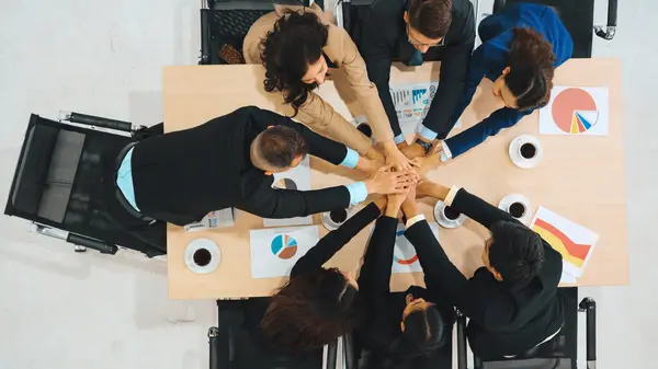 Happy business people celebrate teamwork success together with joy at office table shot from top view . Young businessman and businesswoman workers express cheerful victory show unity support . Jivy