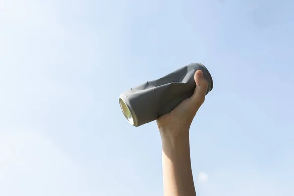 Recyclable can waste held in hand up on sky-like isolated background. Hand holding can waste for recycle reduce and reuse concept to promote clean environment with effective recycling management. Gyre