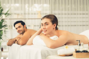 Lüks spa salonlarında sıcak mum ışığında cilt bakımı gören mutlu çift müşterisi. Sağlık kaplıcasında güzellik tedavisiyle tuz temizliği. Sessiz.