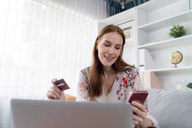 Genç mutlu kadın internetten alışveriş yaparak ürün satın alırken aynı zamanda internet üzerinden online ödeme sistemi ile çevrimiçi mağaza platformundan en yüksek siber güvenlik tarafından korunan ürünler sipariş ediyor.