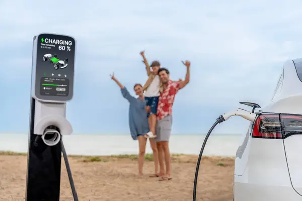Ev充電ステーションから電気自動車でバッテリーを充電するビーチで旅行する代替家族旅行は 明るく幸せな家族が海岸の背景を楽しんでいます パーペチュアル — ストック写真