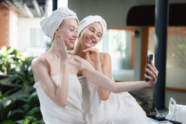 Beyaz havluyla güzel ciltli bir çift güzel kadın açık havada barışçıl doğal çevreyle çevrili bir şekilde fotoğraf çekiyorlar. Güzellik ve sağlıklı spa konsepti. Huzur.