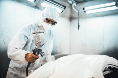 Tam korumalı ekipmanlı otomotiv işçisi sprey tabanca ya da oda atölyesindeki solunum cihazı boyasıyla araba kaportasına ustalıkla renk boyası uygular. Tamir için araba boyama servisi. Oxus.