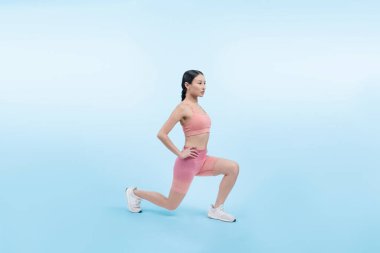 Spor giyimli çekici Asyalı kadın spor egzersizlerinden önce esneme hareketleri yapıyor. Stüdyo çekimlerinde ısınan atletik bir kadınla sağlıklı vücut bakımı egzersizi. Kuvvetli