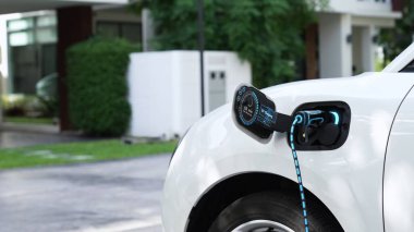 Elektrikli araba EV şarj kablosu ile şarj olmak için şarj istasyonuna bağlı. Geleceğin yenilikçi EV arabası ve enerji sürdürülebilirliği. Akıllı ve fütüristik ev enerjisi altyapısı. İnceleyin