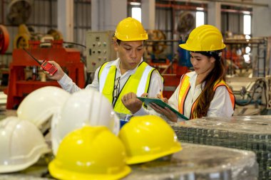 Fabrika ustabaşı ve mühendis çelik makinesi ve ağır endüstriyel malzeme kalitesinde ürün teftişi yapıyor. Makine güvenliği ve kalite kontrollü metal levha üretimi. Örnek gösteriliyor