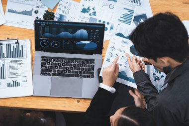 Çok ırklı analist ekibi toplantı masasındaki finansal verileri analiz etmek için BI Fintech yazılımı kullanıyor. Finansal konsol veri ekranında pazarlama göstergesi için analiz edilmiş grafikle birlikte. Uyum