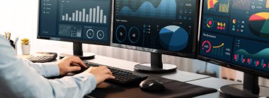 Analizci veri analizi ya da bilgisayar monitöründeki BI gösterge paneli üzerinde çalışıyor. Ticari pazarlama ve strateji planlaması için Fintech 'in şirket ofisindeki finansal verilerini analiz eden bir işadamı. Önde.