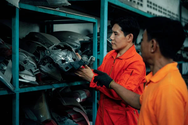 Mechanic worker inspect spare vehicle parts stored in inventory at automotive service. Reusing car components, optimizing resource and availability of spare part for repair and maintenance. Oxus
