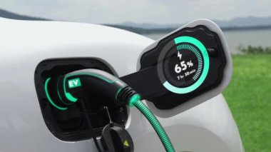 Elektrikli araba şarj istasyonuna bağlanır, EV şarj kablosu ile pili şarj edilir doğası gereği akıllı dijital batarya durum hologramı görüntülenir. Geleceğin yeşil enerji altyapısı. İnceleyin